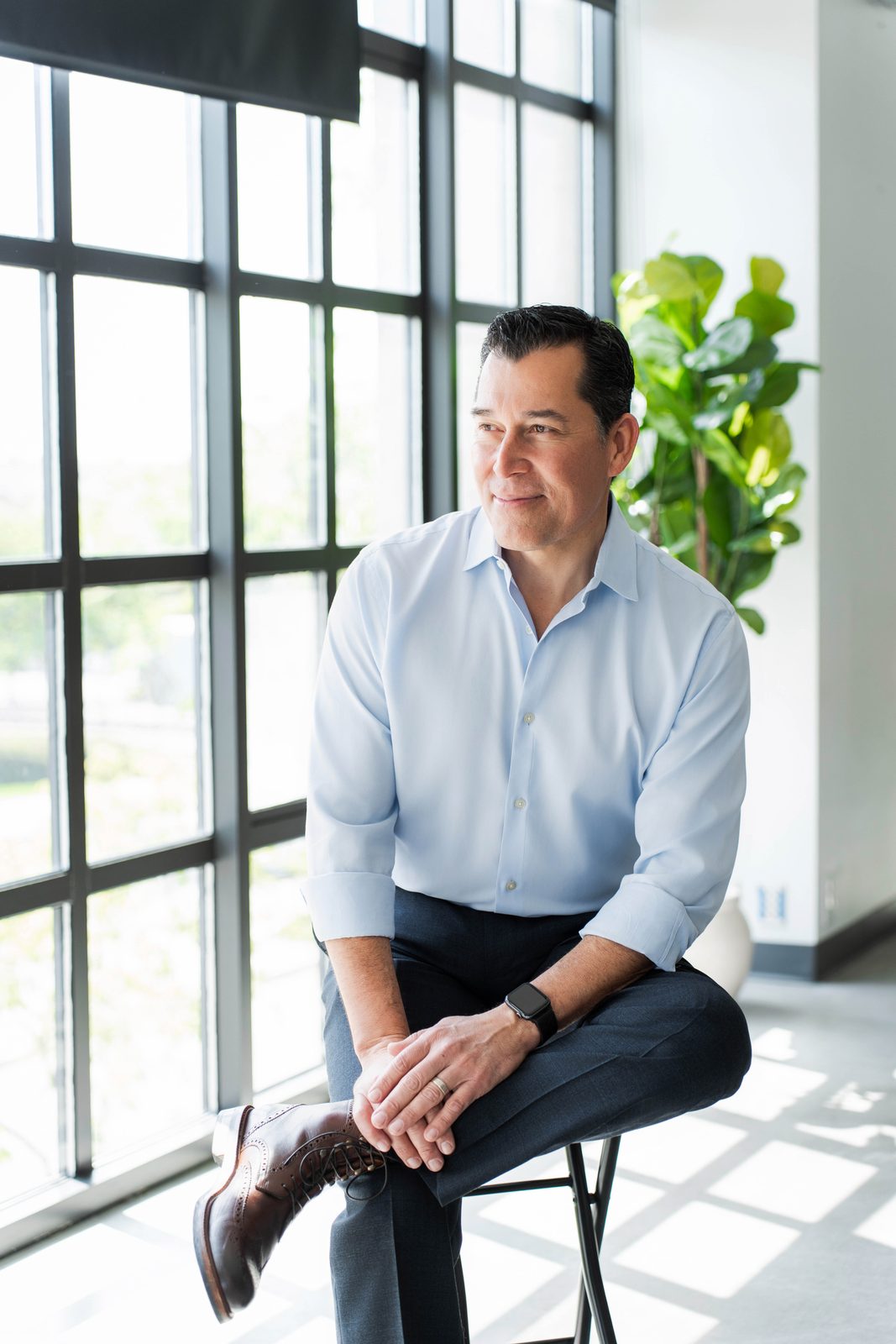 John Abril seated in a light blue shirt at his Ontario office